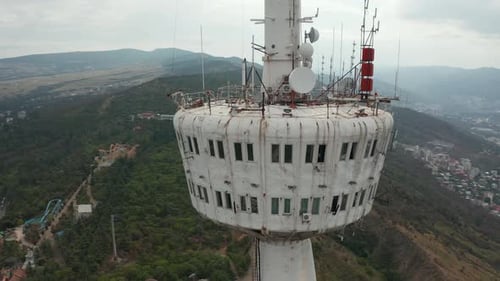 Rotating close up of Tbilisi TV tower in Mtatsminda park. Pan to left. City of Tbilisi and mountains