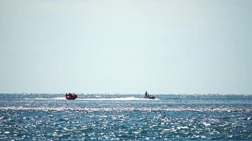 Jet Ski Pulls Raft Across Sparkling Ocean