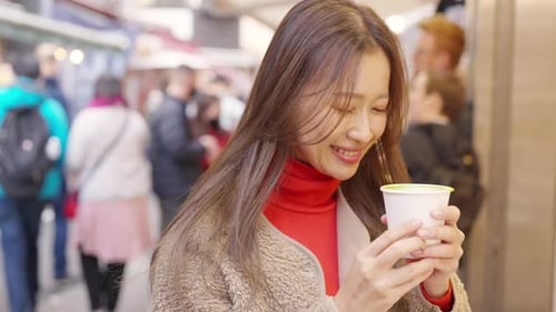 Mujer asiática en 4K bebiendo té verde con leche caliente en un mercado callejero de la ciudad de Tokio, Japón