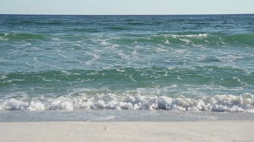 Close up of light waves crashing on white sand beach
