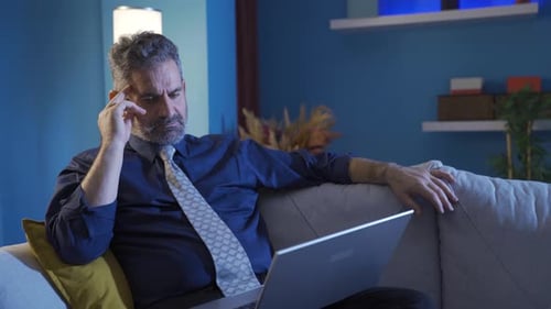 Man Working on Laptop in Living Room at Night