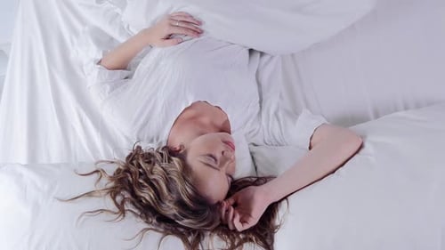Cute Young Woman Sleeping in Bed Waking Up and Smiling at Camera