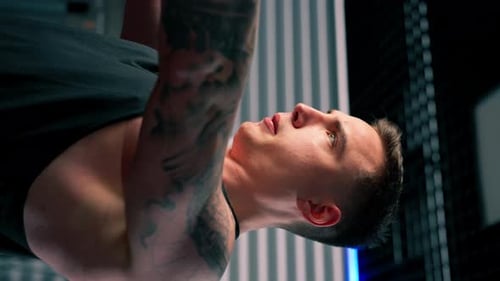 Vertical Video Close Up in the Gym Young Handsome Guy with Tattoos in a Black Tshirt Does Exercises