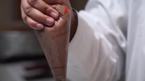 Icing Cake with Chocolate Rosettes in a Kitchen