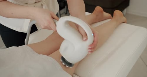 Woman Receiving Leg Massage with Electric Massager