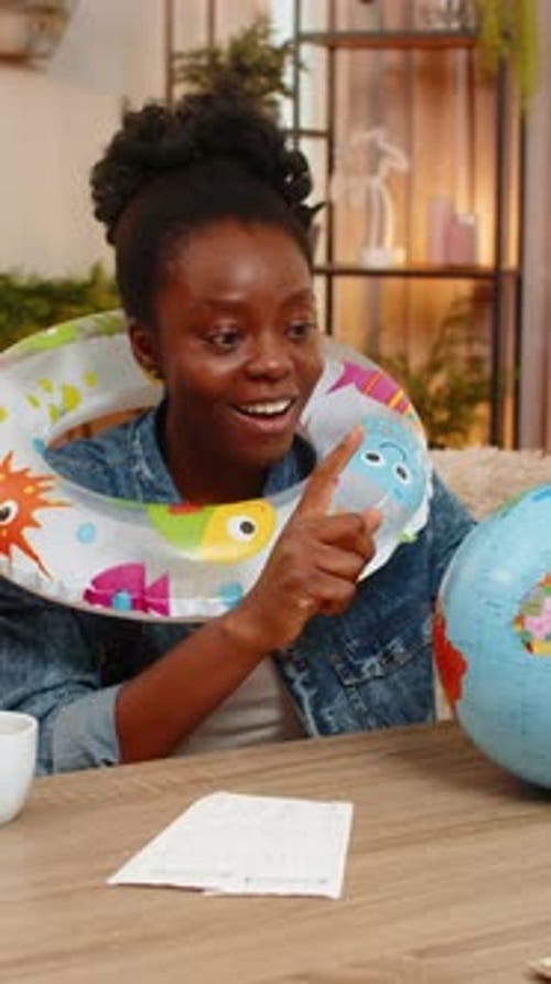 Enthusiastic Woman Planning Vacation at Home with Globe