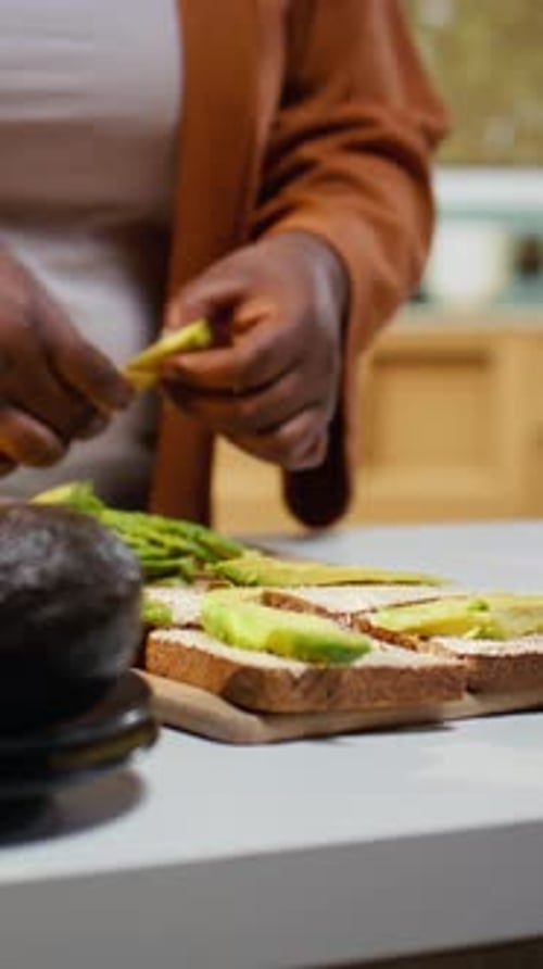 Woman Prepares Avocado Toast at Kitchen Counter