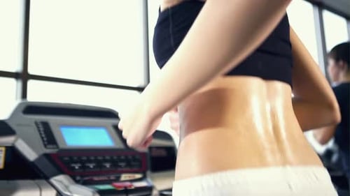 Back View of Pretty Young Woman Athlete Running on Treadmill in Gym