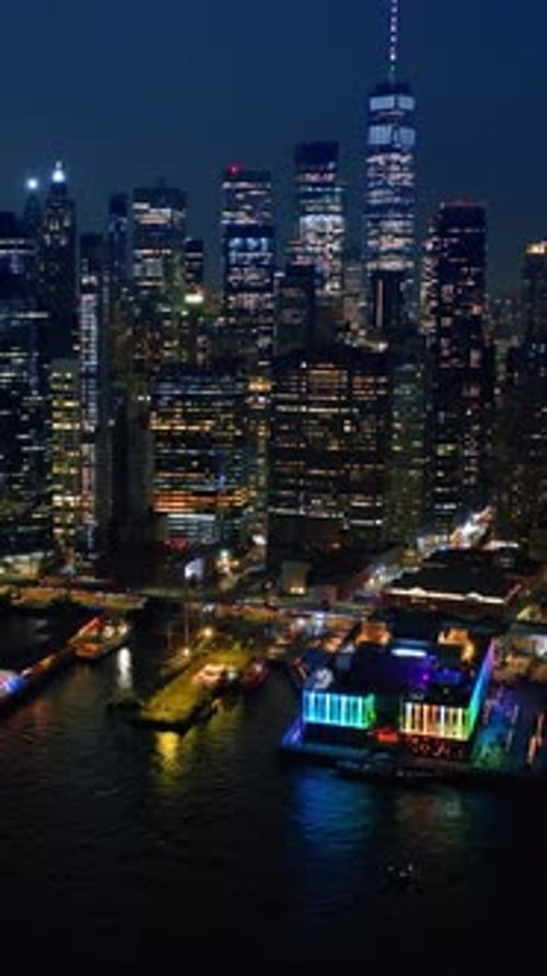 Approaching one of the multiple piers of New York with neon illumination from above the river.