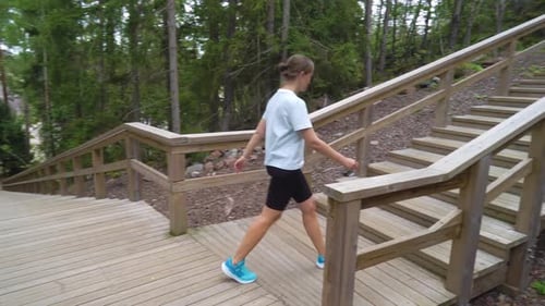 Woman Walking Up Long Staircase in Forest