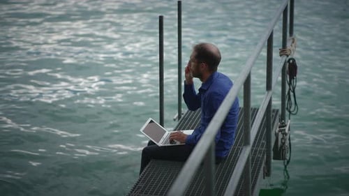 Man Working on Laptop by Rippling Lake
