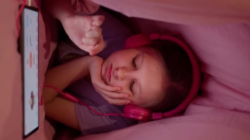 Child Using Tablet with Headphones in Bed