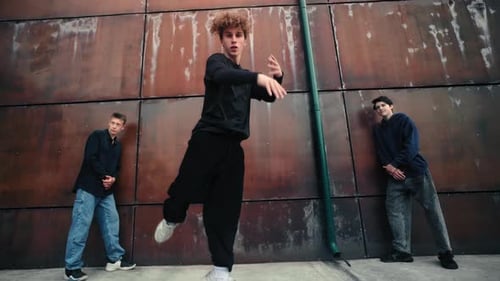 Rothaariger Breakdancer spielt dynamische Streetdance-Moves mit zwei Crewmitgliedern Near Contemporary