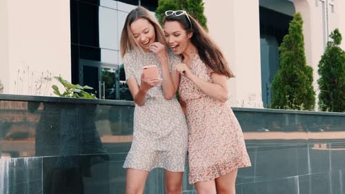 Two young beautiful women using phone apps