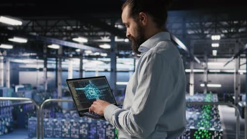 Technician Holding Laptop Walking on Server Farm Platform