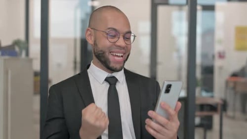 Excited Businessman Checks Smartphone in Office