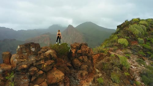 Woman Standing Atop Hill Overlooking Mountains