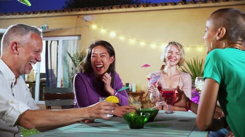 Friends Laughing Over Cocktails at Evening Party