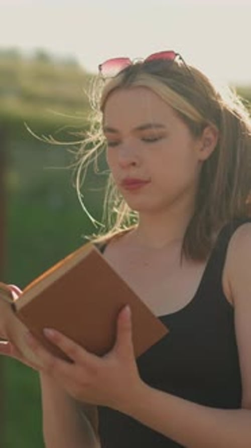 Young Woman Reads Book Outdoors on a Sunny Day