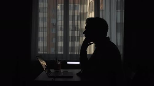 Pensive Businessman Thinking at Laptop in Dark Home Office