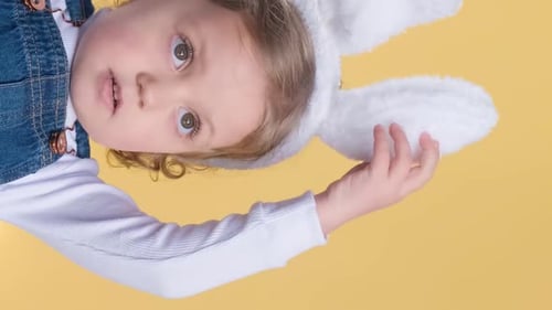 Child with Bunny Ears on Yellow Background