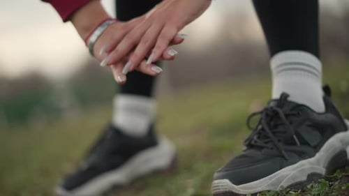 Closeup Caucasian Woman Tying Running Shoe Smartwatch On Wrist Grassy Park Ground Focused Warmup