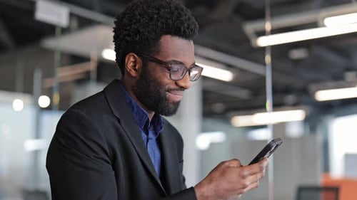 Happy Businessman Using Smartphone in Modern Office