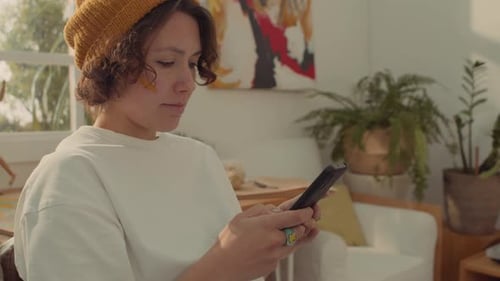 Cheerful Female Student Typing on Smartphone and Laughing