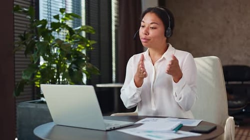 Confident Woman Using Headset and Laptop for Video Conference at Office