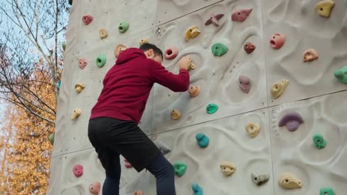 Young Man Climbing an Outdoor Rock Wall