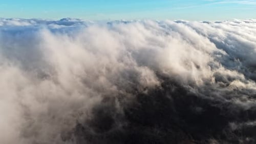 Breathtaking Aerial Shot of Clouds Sweeping Over Mountain Peaks