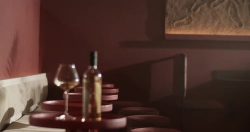 Wine Bottle and Glass Placed on Red Bar Table