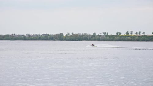 A water scooter sailing Through the Lake, Creating a Splash of White Water in its Wake - Wide slow m