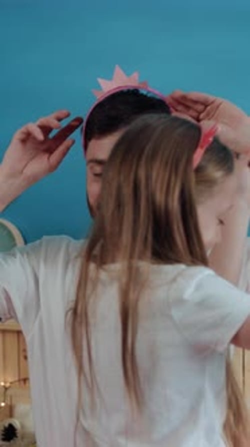 A Man Adorns a Girls Head with a Pink Headband Dancing Joyfully