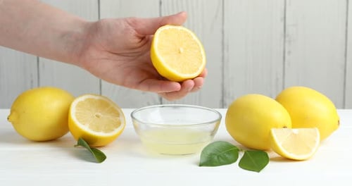Squeezing Fresh Lemon Juice into Bowl on Table