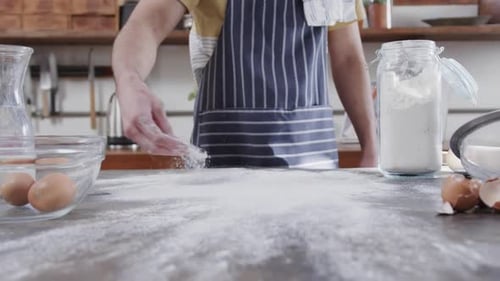 Midsection of caucasian man preparing bread dough in kitchen, copy space, slow motion