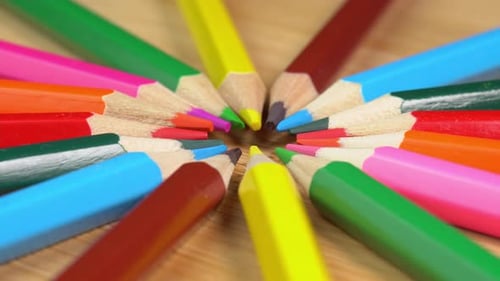 Colorful pencils rotate as sun rays background. Rainbow pencils for drawing. Assortment of colored