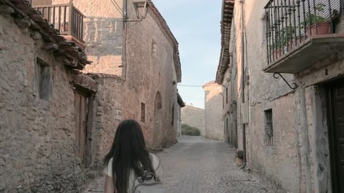 Attractive brunette girl walking through the narrow streets of a medieval tourist town. Tourist visi