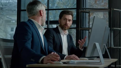 Businessmen Collaborate on Project at Computer in Office
