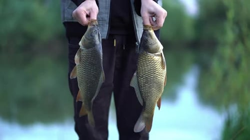 Man Holding Two Fish He Caught Outdoors