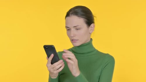 Beautiful Woman Browsing Smartphone on Yellow Background