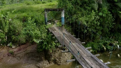 Fahren Sie entlang einer alten Holzbrücke, die auf die andere Seite eines tropischen Flusses führt