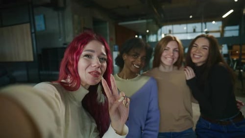 Cheerful Young Women Waving in Casual Office Selfie