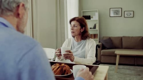Senior couple having coffee and cake together at home