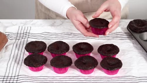 Piping Chocolate Ganache Frosting on Top of Chocolate Cupcakes