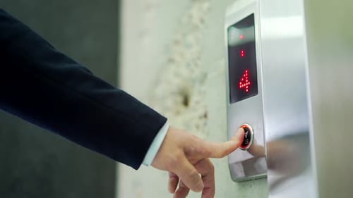 Die
Hand des Mannes drückt die Taste zum Herunterfahren des Aufzugs. Nahaufnahme eines männlichen Fingers, der durch Drücken den Aufzug
erreicht