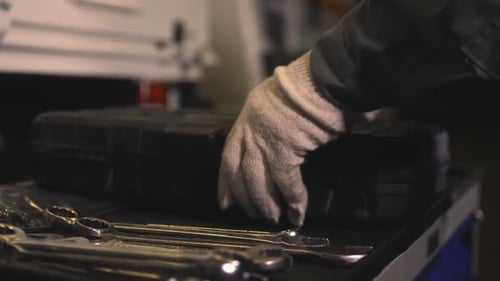 Trabajador coloca una caja de herramientas sobre la mesa con llaves en el taller