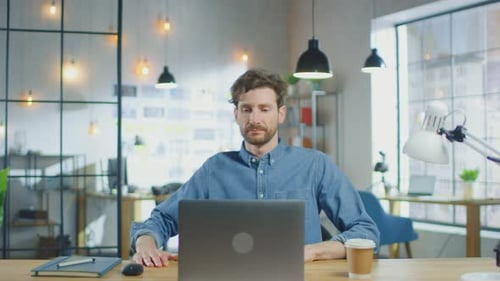 Young Handsome Man Works on a Laptop Computer in Cool Creative Agency in a Loft Office. He has a Ta
