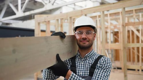 Construction Worker Carrying Wood Plank on Shoulder