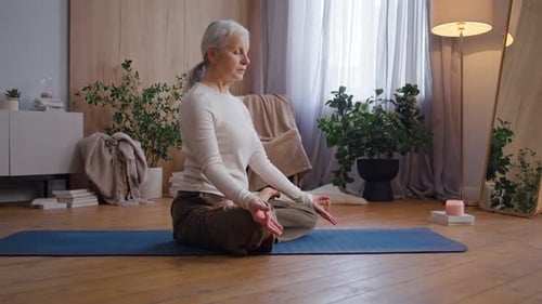 Senior Woman Meditates After Yoga Session in Bright Home Studio